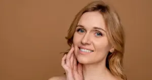 Woman with a smooth, clear complexion touching her face, illustrating the radiant, natural anti-aging results from Rejuran in Hoboken, NJ.